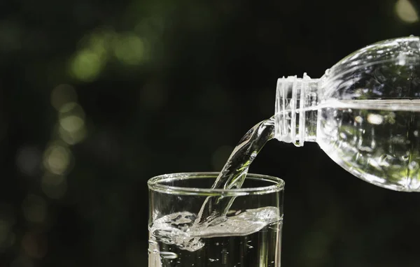 Verter agua de la botella en el vaso sobre un fondo borroso . — Foto de Stock