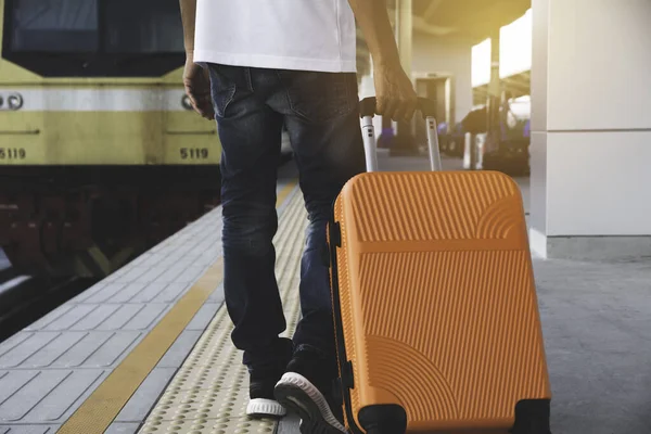 Hombre arrastrando maleta naranja bolsa de equipaje, caminando en el tren stati —  Fotos de Stock