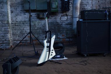 Beyaz elektro gitar ve amfi endüstriyel zemin üzerine.