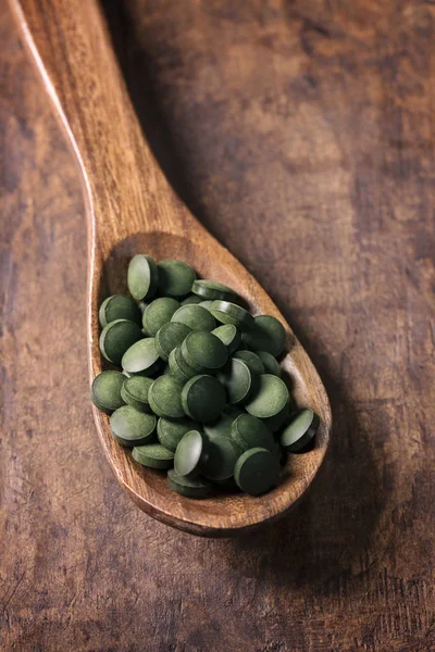 Tabletas Espirulina Una Cuchara Sobre Fondo Madera —  Fotos de Stock