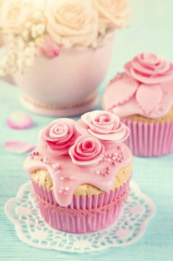 Mavi ahşap arka plan üzerinde pembe çiçekler ile cupcakes