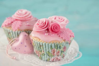 Mavi ahşap arka plan üzerinde pembe çiçekler ile cupcakes