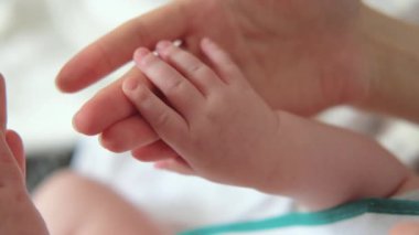 Anne Bebek elini tutuyor. Yeni doğan bebek anne elinde el