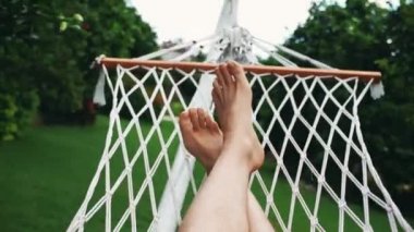 Tropikal bahçede hamak üzerinde sallanan bir adam. Seyahat ve tatil konsepti. 4k video görüntüleri