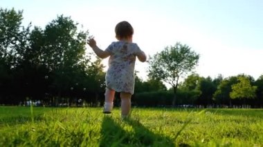 Yaz aylarında yeşil çim üzerinde sabun kabarcıklar yakalamak küçük bebek kız. Slow Motion 120 fps, mutlu çocukluk ve ebeveynlik konsepti.