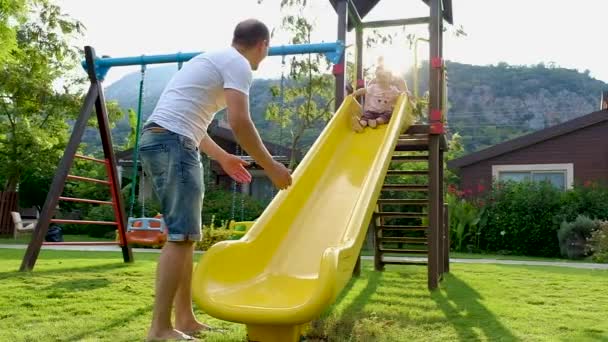 有趣可爱的女婴与她的父母在操场滑梯上玩 幸福的家庭在日落的公园里玩得开心 完整的高清慢镜头视频画面 — 图库视频影像