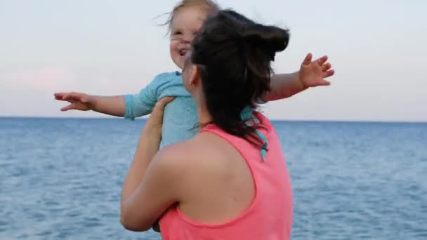 彼女の小さな女の赤ちゃんと若い母親は夏の日にビーチでの楽しみを持っています 幸せな家族のコンセプト 幸せな子供時代4K ビデオ映像 — ストック動画
