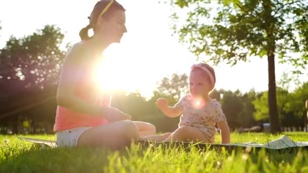 Niña Sentada Con Madre Sobre Hierba Verde Verano Slow Motion — Vídeos de Stock