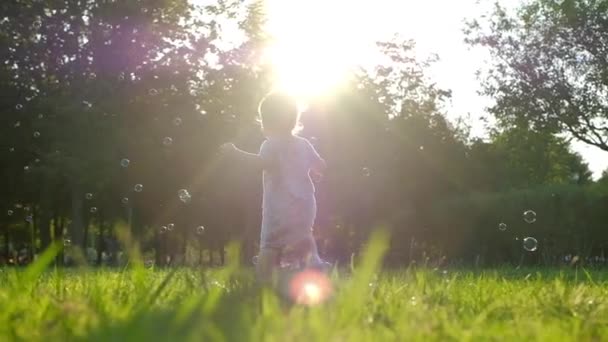 Ein Kleines Mädchen Fängt Sommer Seifenblasen Auf Grünem Gras Zeitlupe — Stockvideo