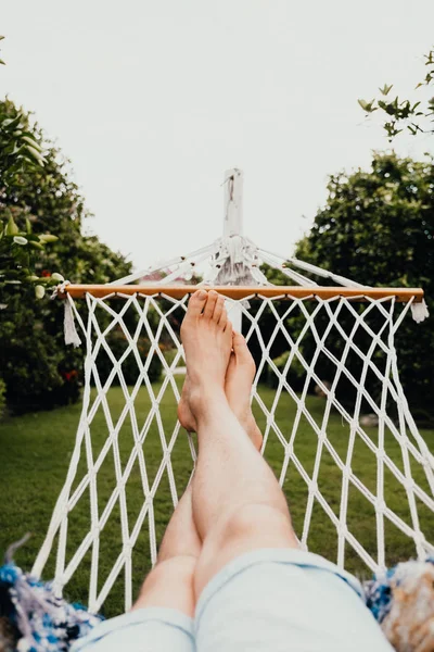 Ein Mann ruht sich auf einer Hängematte im tropischen Garten aus. Reise- und Urlaubskonzept — Stockfoto