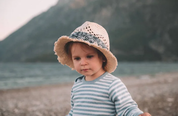 Χαριτωμένο μικρό κοριτσάκι με το καπέλο που παίζει σε μια παραλία στην καλοκαιρινή μέρα. Οικογενειακά ταξίδια και διακοπές έννοια — Φωτογραφία Αρχείου