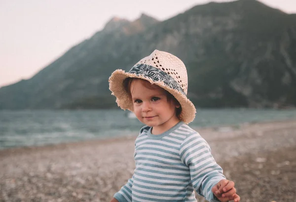 Linda niña con sombrero jugando en una playa en el día de verano. Viajes en familia y concepto de vacaciones — Foto de Stock