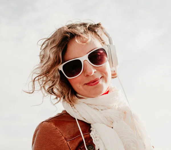 Молода жінка в білих навушниках слухає музику яскравий фон неба в літній день — стокове фото