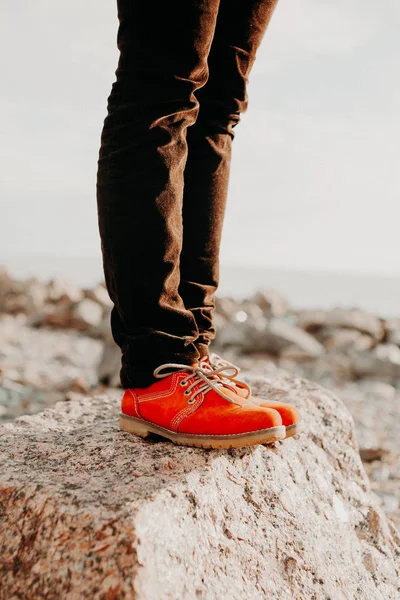 Frau in lässigen orangefarbenen Schuhen und Jeans, die an einem Sommertag auf einem Stein steht. Modekonzept. — Stockfoto