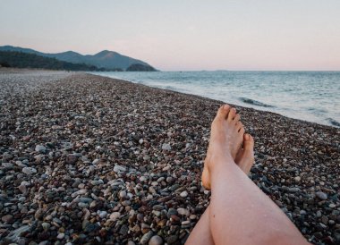 Bir yaz günü denize karşı bir çakıl taş plaj portre kadının ayakta. Seyahat ve tatil kavramı. Geri kalan genç kadın vardır