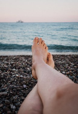 Bir yaz günü denize karşı bir çakıl taş plaj portre kadının ayakta. Seyahat ve tatil kavramı. Geri kalan genç kadın vardır