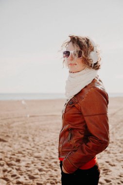 Genç kadın yaz gün plajda müzik dinlemek bir beyaz kulaklık