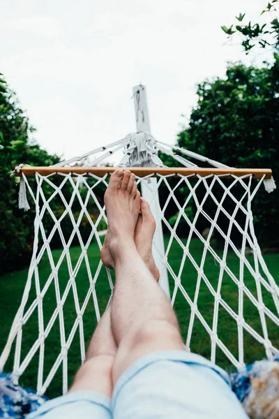 Un uomo ha un resto che si trova su un hammock al giardino tropicale. Viaggio e concetto di vacanza — Foto Stock