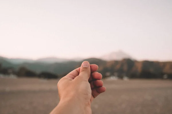 Une main simule la tenue d'une photo, d'une carte postale ou d'une note sur un beau coucher de soleil sur les montagnes à la plage en été . — Photo