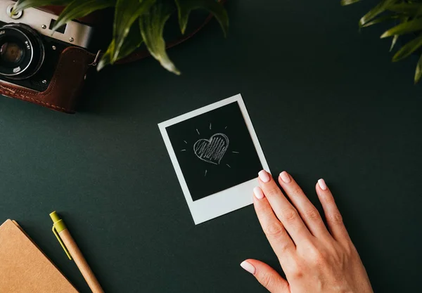 Female hand holds a polaroid picture with a heart — Stock Photo, Image