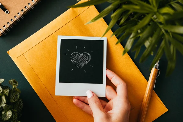 Flat lay female hand holding a polaroid picture — Stock Photo, Image