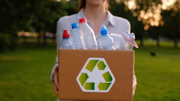 Jonge, onbekende vrouw houdt en overhandigt een doos met plastic flessen — Stockvideo