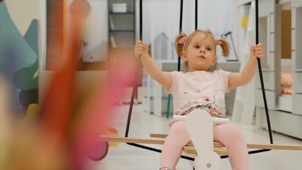 Charmantes kleines Mädchen schwankt auf einer Schaukel in Form eines Flugzeugs — Stockvideo