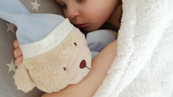 Close-up of a cute sleeping beautiful girl on a pillow with a bear — Stock Video