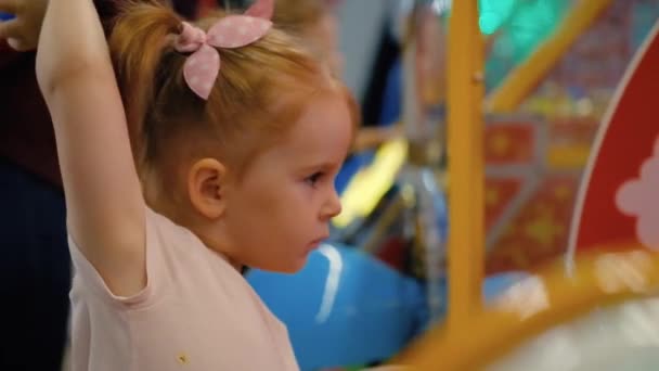 Kleines süßes Mädchen spielt während eines Urlaubs im Spielzimmer an einem Spielautomaten — Stockvideo