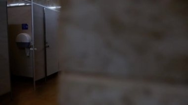Kamera yavaş yavaş boş bir kamu erkekler tuvaletine girer
