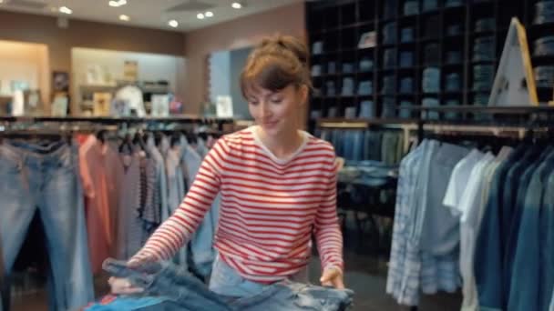 Mulher bonita em roupas casuais é alisar jeans deitado em uma pilha — Vídeo de Stock