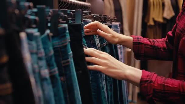 Seitenansicht einer jungen hübschen Frau in Freizeitkleidung wählt Jeans — Stockvideo