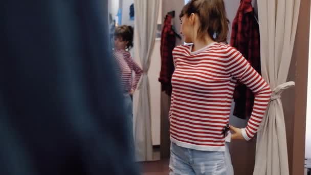 Charmig ung kvinna försöker på snygga jeans från ljus denim — Stockvideo