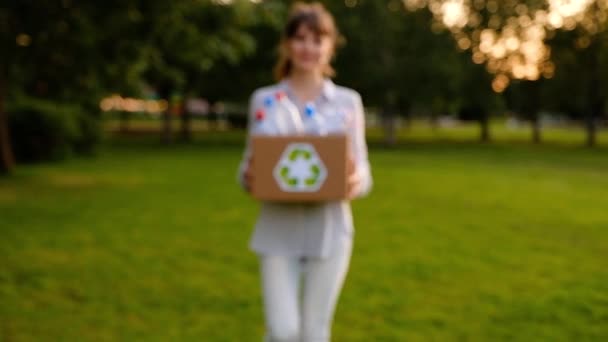 Молодая неопознанная женщина держит в руках коробку с пластиковыми бутылками — стоковое видео