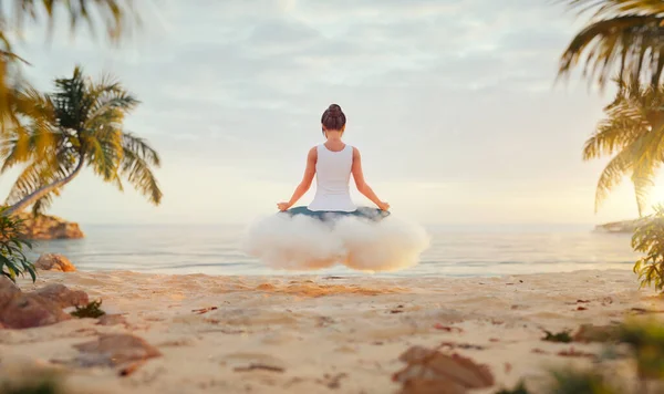在热带海滩上 一位年轻快乐无忧无虑的女人坐在白云上享受美丽的落日 瑜伽和冥想的概念 — 图库照片