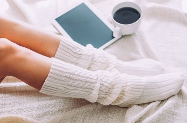 Yatağın üzerine kadın bacakları yakın çekim. Genç bayan evde kalmaktan hoşlanıyor..