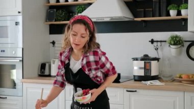 Dertsiz, mutlu, genç kadın ev hanımı tek başına yemek pişiriyor.