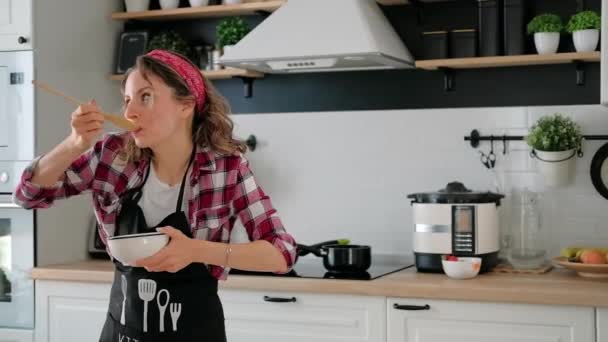 Безтурботний щаслива молода домогосподарка танцює сама готуючи їжу — стокове відео