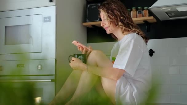 Jeune jolie femme boit du café assis à sa cuisine à la maison — Video