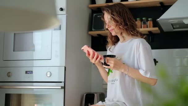 Joven bonita mujer bebe café sentado en su cocina en casa — Vídeos de Stock