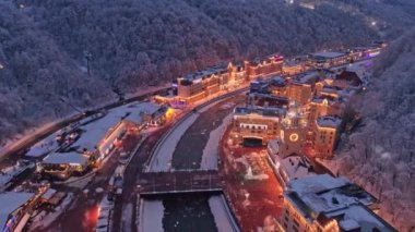 Hava drone fly kış Rosa Khutor akşam aydınlatma ile yukarıda. Beyaz kış kar orman çevresinde. Alpler