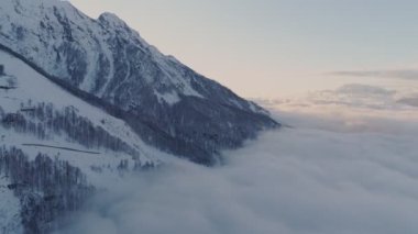 Havadan görünümü. Karla kaplı dağ yoğun bulutlar yukarıda geniş atış. Drone fly dağlarda günbatımı sırasında inanılmaz bulutlar üzerinde. Kayak tesisi.