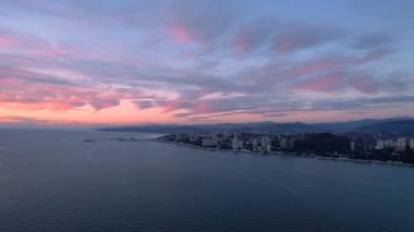 Gün batımı sırasında denizde drone hava şehir kıyı şeridi.