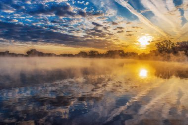 Arka planda yükselen güneş ile Puslu göl