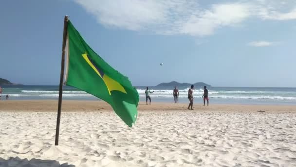 Ilha Grande, Rio de Janeiro, Brezilya - Kasım 2018. Lopez Mendes Plajında Futbol Oynayan İnsanların Arkaplanında Brezilya Bayrağı sallamak. — Stok video