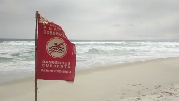 Geschrieben in Portugiesisch und Englisch "Gefährliche Strömungen" Rote Flagge am Strand von Rio de Janeiro, Brasilien. Kein Schwimmzeichen als Warnung, dass Wasser in diesem Bereich verboten ist. — Stockvideo