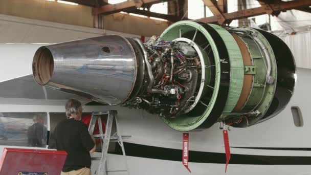 Great Falls, Montana, EUA - JULHO 2015. Montagem do motor do avião de passageiros em manutenção. O engenheiro verifica a turbina da aeronave. Reparação de aeronaves no hangar. Construção de aeronaves . — Vídeo de Stock