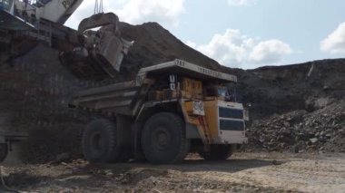 Kemerovo, Russia - August, 2019. Large Excavator Bucket Loading Heavy Dumb Truck At The Coal Mining Area.