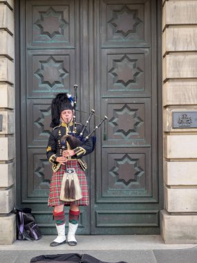 EDINBURGH SCOTLAND - JULY 26: A Scotsman wearing traditional Scottish outfit playing the bagpipes along the Royal Mile on July 26, 2017 in Edinburgh, Scotland. There are many pipers busking. clipart