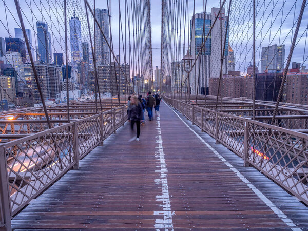 New York, New York - March 30, 2018: The famous Brooklyn Bridge at sunset in New York City. The Brooklyn Bridge spans the Hudson River and connects Manhattan and Brooklyn